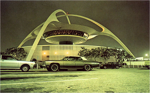 Cars from the 1970s parked in front of a flying saucer,  sci-fi themed restaurant located at the Los Angeles International Airport.